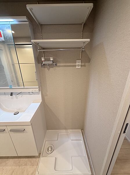 【洗面室】洗濯機置場の上部には棚が設けられており、タオルや洗濯用品などをすっきり収納できます。設置可能な洗濯機のサイズなどは、現地にてお確かめください。