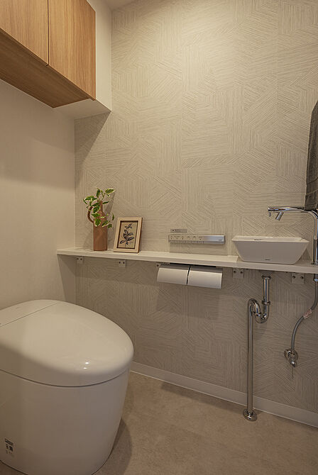 【トイレ】スタイリッシュなデザインが魅力的な、温水洗浄便座付きのトイレです。独立した手洗い器を設置しているため、使用後すぐに手洗いができます。収納に便利な吊戸棚付きです。