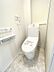 トイレ：清潔感あふれるトイレは、日々の暮らしに心地よさをもたらします。壁にはタオルリングと収納棚を設置し、機能性にも配慮しました。