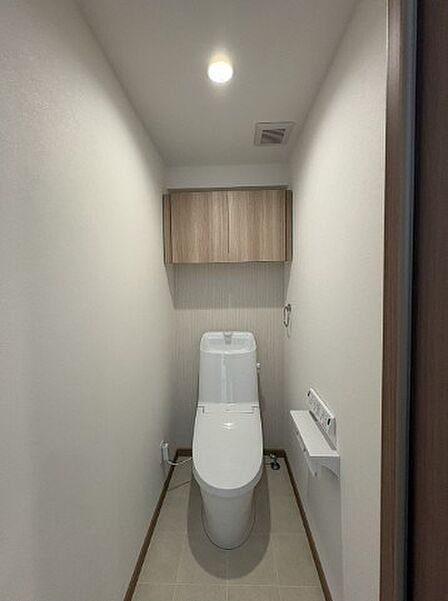 清潔感あふれるトイレ空間。上部収納で空間を有効活用し、洗練されたデザインが毎日の生活に快適さをもたらします。