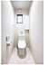 トイレ：清潔感のある白い空間に、窓からの自然光が差し込むトイレです。収納棚もあり、機能性も兼ね備えています。