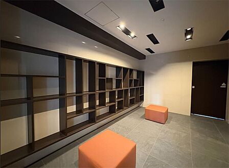 多様なサイズの棚と温かみのある照明が印象的なエントランス。居住者の交流を育む空間です。