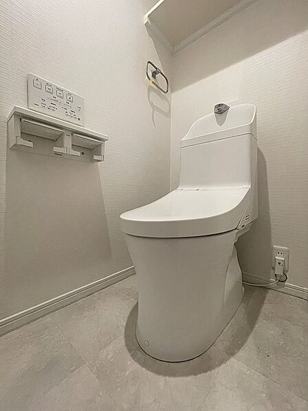 清潔感あふれる白いトイレ空間。壁のリモコンで快適な操作が可能です。快適な毎日をサポートします。