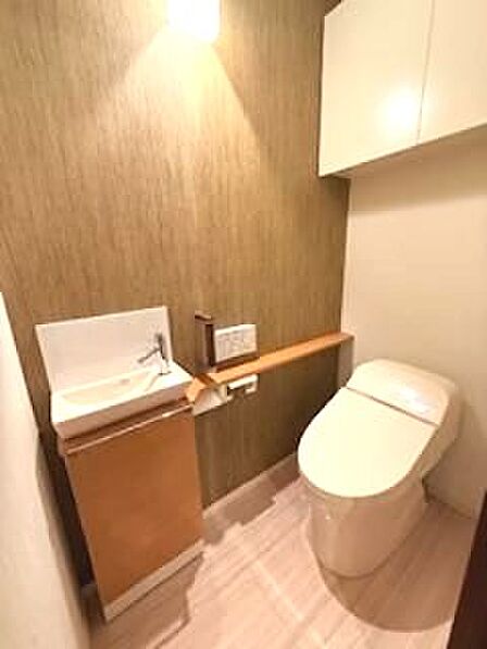 落ち着いた色調の壁紙と間接照明が、心地よい空間を演出するトイレ。手洗いカウンター付きで、清潔感も保ちやすい仕様です。