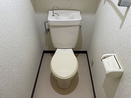 清潔感のある壁紙で仕上げられたトイレです。上部の棚は芳香剤や小物の設置に活用できます。