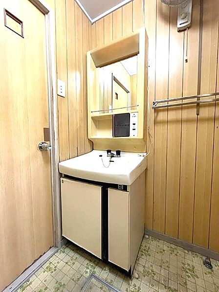 木目調の壁が温かみを感じさせる洗面台。鏡下には収納スペースも備わり、日用品の整理に便利です。
