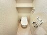 トイレ：温水洗浄便座と便利な棚付きのトイレ空間。落ち着いた色合いのクロスが、リラックスできるひとときを演出します。