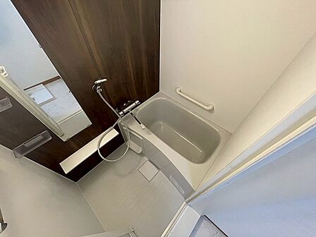 ダークブラウンの壁が落ち着いた雰囲気を醸し出す浴室。浴槽には手すりも設置され、安心感のあるバスタイムをお過ごしいただけます。一日の疲れを癒す空間です。