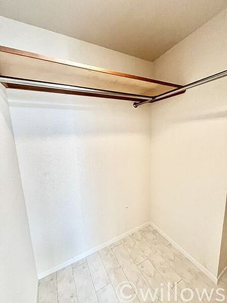 服をたっぷり掛けられるL字型のハンガーパイプを備えたウォークインクローゼット。上部の棚にはバッグや季節物の荷物もすっきり収納可能です。衣類をしっかり整理でき、居室スペースを広く活用できます
