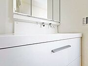 「洗面化粧台」白を基調とした清潔感溢れるデザインの洗面化粧台です。三面鏡の裏側や足元のキャビネットなど、収納豊富で実用的な洗面空間です。
