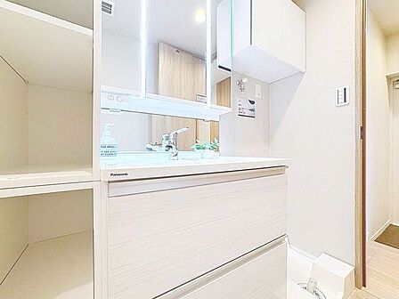 「洗面化粧台」白を基調とした清潔感溢れるデザインの洗面化粧台です。三面鏡の裏側や足元のキャビネットなど、収納豊富で実用的な洗面空間です。