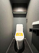 吊戸棚を備えたトイレスペース。シックな印象のクロスを採用