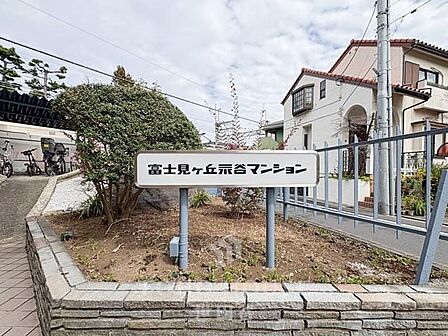 富士見ヶ丘谷マンションの入り口です。緑豊かな植栽と、自転車も停めやすいスペースがあり、家族の毎日を快適にサポートします。