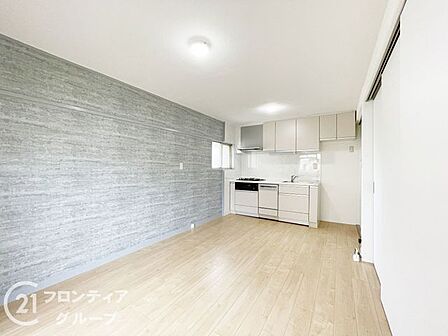 明るい木目のフローリングとグレーのアクセントクロスが調和する空間です。間仕切りを開放すれば、より開放感あふれる広々としたリビングとして、ライフスタイルに合わせた自由なレイアウトが叶えられます