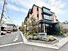 外観：【Exterior】少し離れた場所から望む建物全体の姿。周囲の街並みと調和した、落ち着きのある外観です。