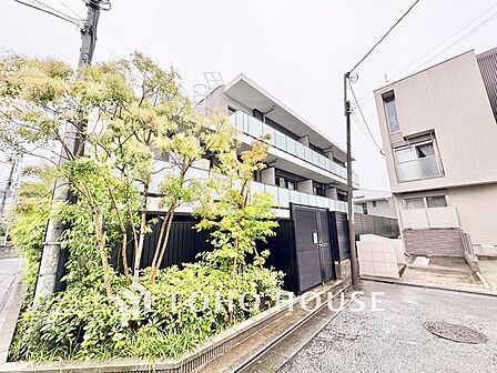 ガラスパネルを贅沢にあしらったバルコニーが光を美しく反射する、意匠性の高い外観デザイン。モノトーンと植栽のコントラストが際立ち、スタイリッシュな雰囲気を醸し出しています。