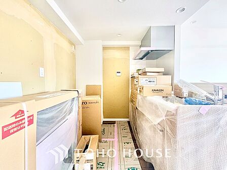 新規交換中のシステムキッチン。調理スペース後方には十分なスペースがあり、家電ラックやカップボードもスッキリ設置可能。ダウンライトのやわらかな光が作業面を明るく照らす機能的な設計です。