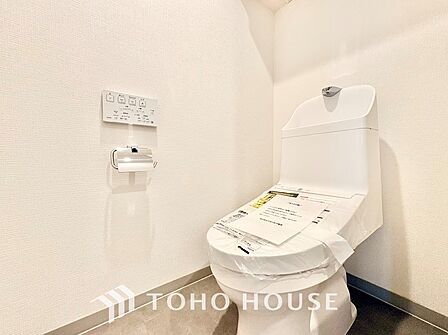壁掛けリモコンでスムーズに操作できる温水洗浄便座を採用。手洗いボウルが一体となった節水タイプで、明るくシンプルなクロスが清潔感のある空間を演出します。