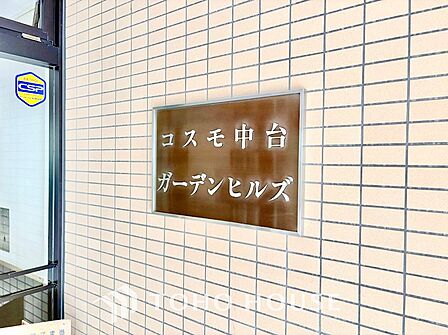 凹凸感が重厚な割り肌調タイルに掲げられた「シティテラス板橋蓮根」のステンレス切り文字サイン。青々とした植栽に映える格調高いエンブレムが、住まい手のステータスと所有欲を満たします。