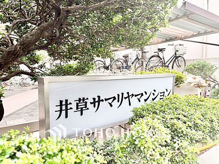 「井草サマリヤマンション」の館銘板。豊かな植栽に囲まれたアプローチは、居住者や訪れる人を温かく迎え入れます。
