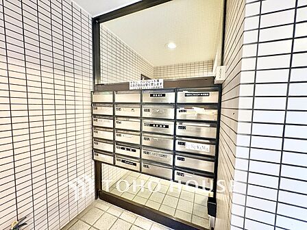 各部屋ごとに綺麗に整列されたダイヤル式のメールボックスです。周囲のタイル壁も清潔に保たれています。
