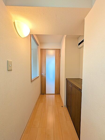 温かみのある照明が優しく迎えてくれる玄関廊下です。木目調のシューズボックスを備え、カウンター天板には小物や花を飾ることも可能。奥のスリットガラス扉から差し込む光が、奥行きと明るさを演出します。