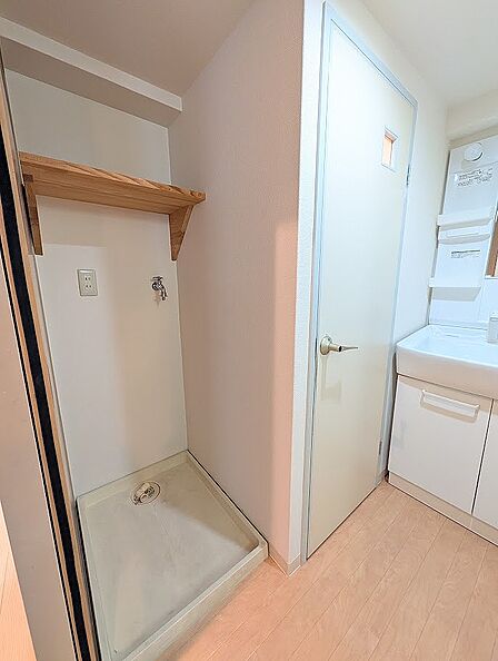 室内洗濯機パンの上部には、洗剤やタオル類をすっきりと収納できる便利な固定棚が設置されています。洗面台や浴室への動線上に位置しており、家事や身支度をスムーズに行える効率的なレイアウトです。