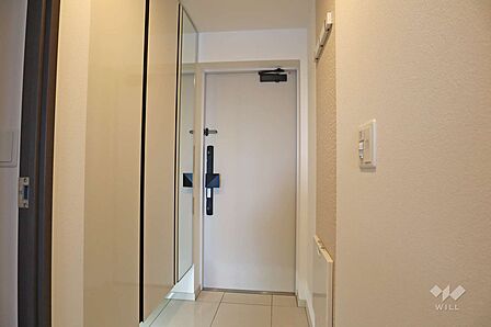 玄関。上まである大容量のシューズクローゼット。鏡やカバン掛けもついています。足元の間接照明もおしゃれです。［2025年5月5日撮影］
