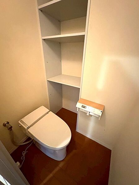 ウォシュレット機能付きのトイレになります。横には収納豊富な棚があります。