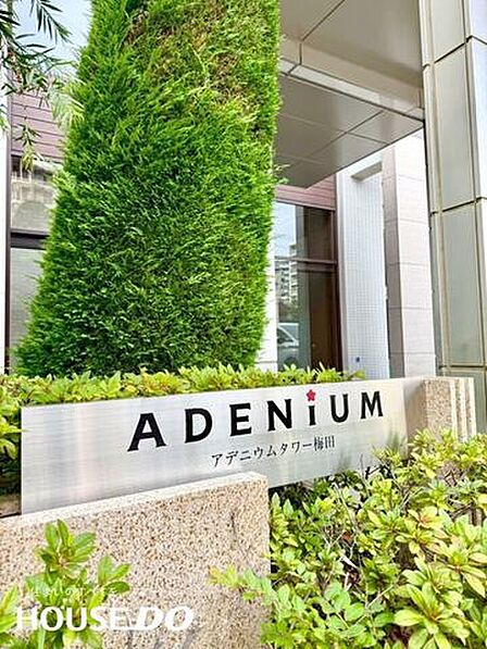 「ADENiUM 」の銘板がシンボリックなエントランスアプローチ。緑の植栽との調和が上質なマンションライフを演出しています。
