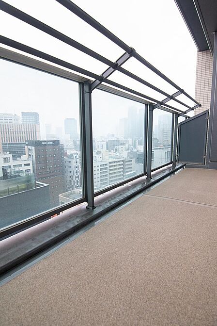 都市の景色を望むバルコニー。ガラス手すりで視界が抜け、洗濯や気分転換にも心地よい屋外空間です。現地（2025年12月）撮影