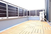 ウッドパネルが敷かれたお洒落な空間。横桟フェンスが視線を遮りつつ、光と風を通します。椅子を置いてリラックスタイムを過ごすなど、セカンドリビングとしても最適な開放感あふれるプライベートエリアです。