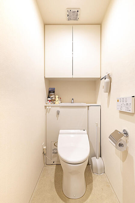 【収納棚付きのトイレ】温水洗浄便座を備え、上部の吊戸棚でストックの収納も安心。清潔感のある独立空間です