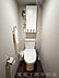トイレ：細部まで、美意識を行き渡らせて。 清潔感のあるトイレ空間には、便利な吊戸棚を完備。限られたスペースだからこそ、機能性とデザイン性を両立し、住まいの隅々まで届くこだわりを感じさせます。
