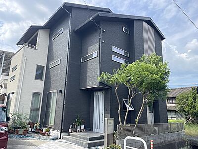 外観：駅家町万能倉にある中古物件。スタイリッシュな外観が魅力のモダンな住まい。採光や風通しが良く、開放感のある空間を実現。広々とした玄関アプローチには植物が彩りを添え、心地よい雰囲気が漂います。