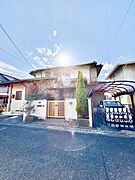 門扉と植栽を含めた正面からの外観写真。玄関位置やアプローチの雰囲気、敷地と建物のバランスを確認できます。