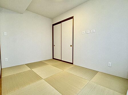 琉球風の縁なし畳がモダンな印象を与える和室には、布団や季節物の収納に便利な大容量の押入れ(またはクローゼット)が備わっており、すっきりとした空間を保てます。