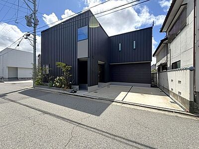外観：シックな黒の縦ラインが洗練された印象を与える、モダンなデザイナーズ風の外観。建物前面には並列でゆったりと駐車できるスペースを確保し、デザイン性と日々の利便性を兼ね備えています。