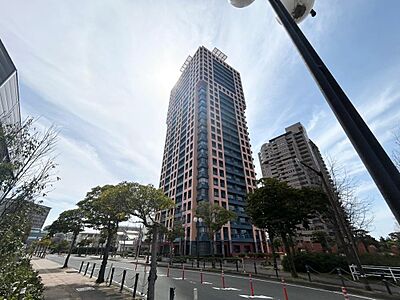 外観：青空に映える個性的な外観のタワーマンション。周辺には街路樹が整備され、開放感のある街並みです。都心での快適な暮らしが期待できます。
