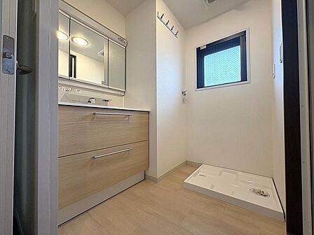 優しい色合いの洗面室。洗濯機横にはコート掛けを設置。ハンガー等の洗濯用品やモップ等の掃除用品を吊るしておけるのは便利ですね。