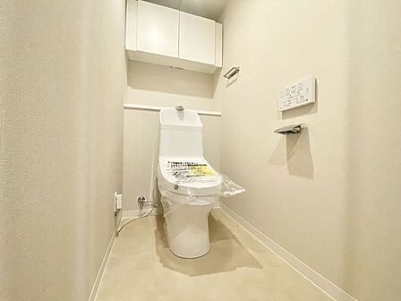 温水洗浄便座付きの清潔感あるトイレ。上部には吊戸棚があり、トイレットペーパーや掃除用品を見せずに収納できます♪