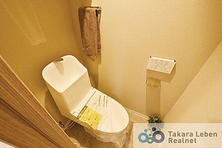 ウォシュレット機能付きのトイレは壁掛けリモコンの上位グレードを採用。便座がスッキリした印象となり、限られた空間を広く見せる効果があります。