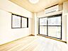 寝室：やさしい陽射しが差し込む寝室は、心地よい眠りへと誘う癒しの空間。木目調の床と白を基調とした壁が、清潔感とやわらかな印象を与え、毎日の疲れをそっと包み込みます。