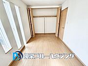 【4連の縦型窓と大型収納のある居室】特徴的な4連スリット窓から光が差し込む設計。壁一面にハンガーパイプ付きのクローゼットを配置。
