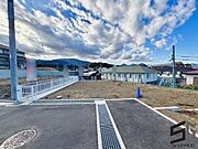 広々とした前面道路に面し、車の出し入れがしやすい現地外観。ゆとりある駐車スペースと開放感のある立地が魅力で、毎日の暮らしに快適さと安心をもたらすマイホームです。
