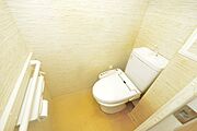 清潔感溢れるホワイトの温水洗浄便座付きトイレです。背面の壁紙にはアクセントクロスを採用し、明るく落ち着いた空間に仕上げています。立ち座りをサポートする手すりやペーパーホルダーも完備し、使い勝手の良さを