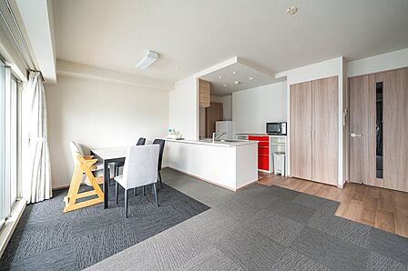 【リビング】広々としたリビング・ダイニング。奥には機能的なキッチン、窓からは開放的な景色が広がり、明るく居心地の良い空間を演出しています。