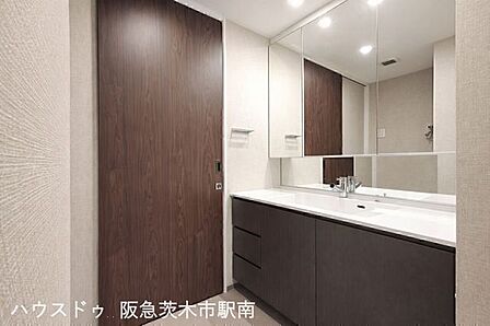 広々とした洗面化粧台。三面鏡と収納も充実しており、朝の身支度も快適に行える使い勝手の良い空間です