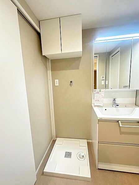 洗濯機置場。上部には吊戸棚があり、消耗品を収納できます