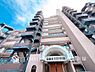 外観：【Appearance】陽光が降り注ぐ青空の下、堂々とした外観が印象的なマンション。ご家族の成長を見守る、安心感のある住まいです。